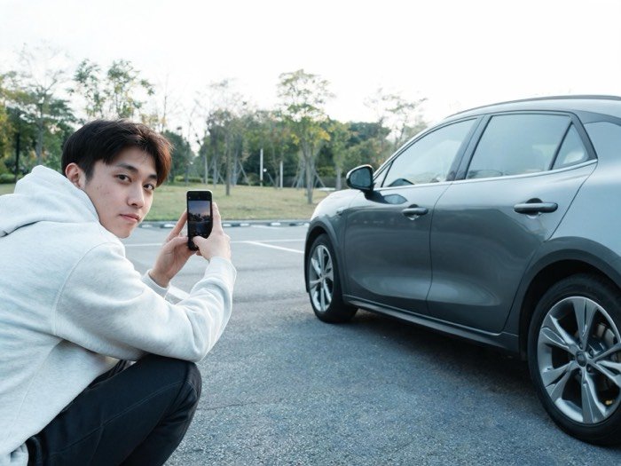 Person fotografiert ihr Auto mit dem Smartphone